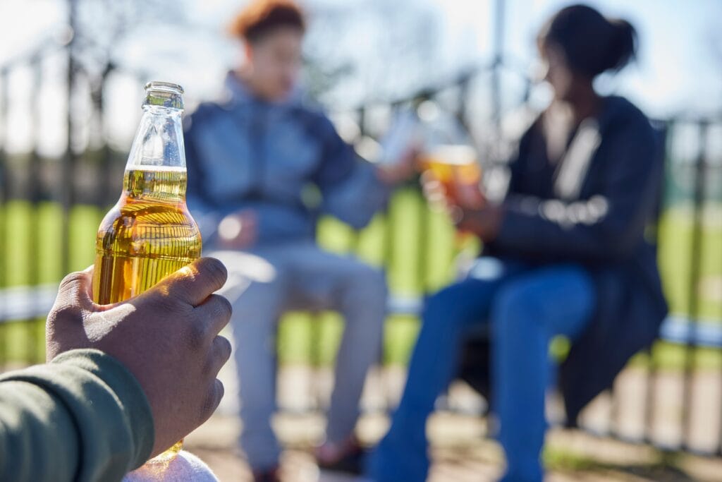 Teens drinking at the park after wondering what happens when you drink alcohol as a teen.
